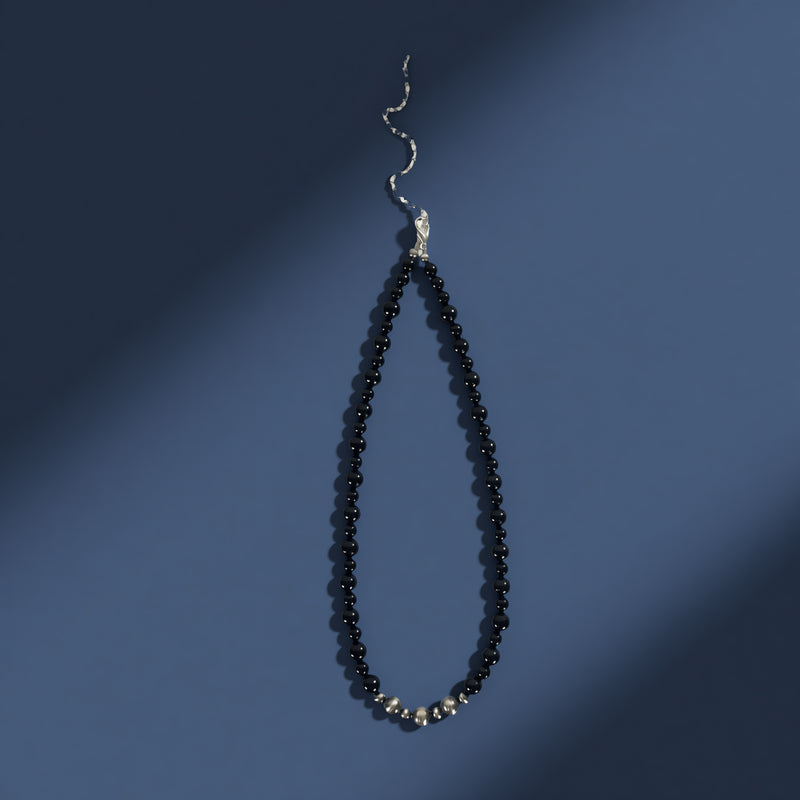 Black beaded necklace with silver clasp on a blue background