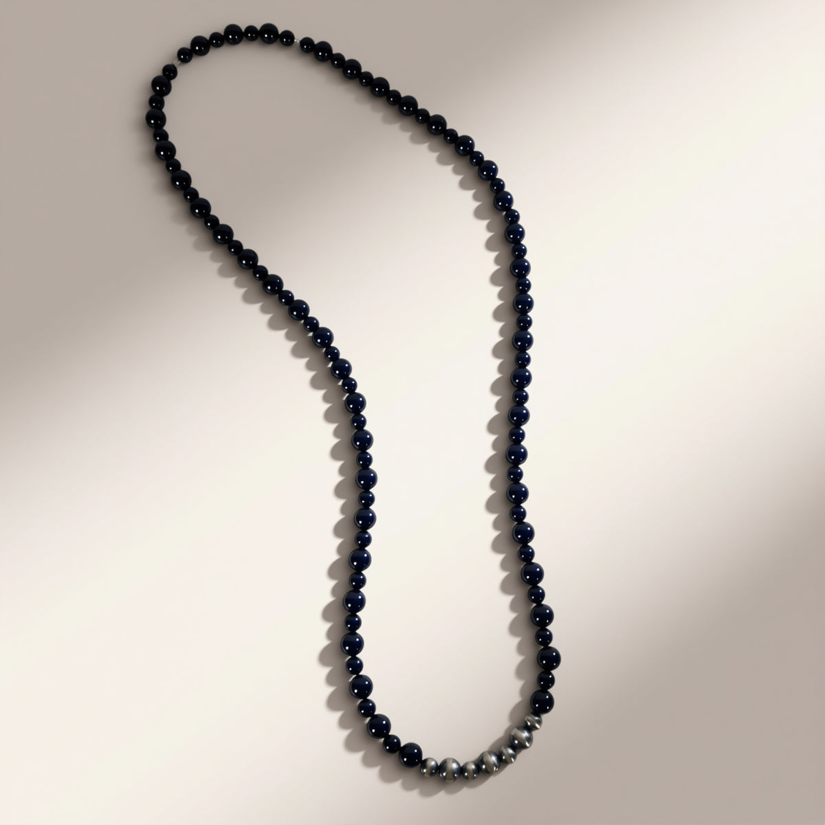 Long necklace with dark beads on a neutral background