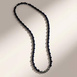 Long necklace with dark beads on a neutral background