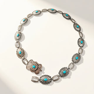 A sterling silver concho-style necklace with turquoise accents, displayed on a clean white background with soft shadows.