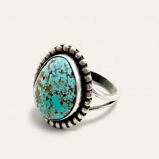 silver ring with turquoise stone on a beige background