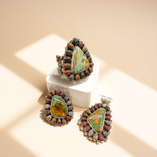 Turquoise jewelry set with cuff, ring, and a pendant on a beige background