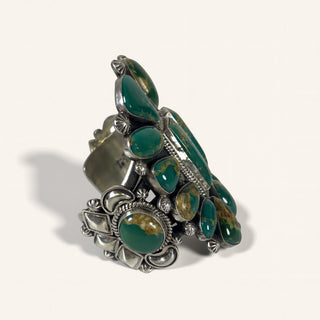 Silver ring with green gemstones on a white background