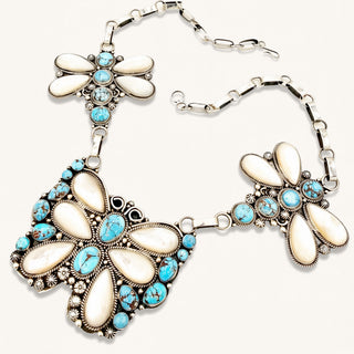 Silver butterfly necklace with turquoise stones on a beige background