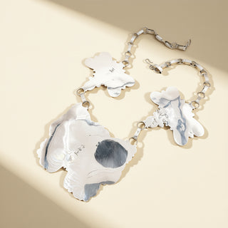 Silver necklace with abstract pendant on a beige background