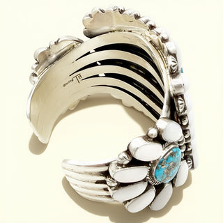 Silver cuff bracelet with turquoise and white stones on a white background