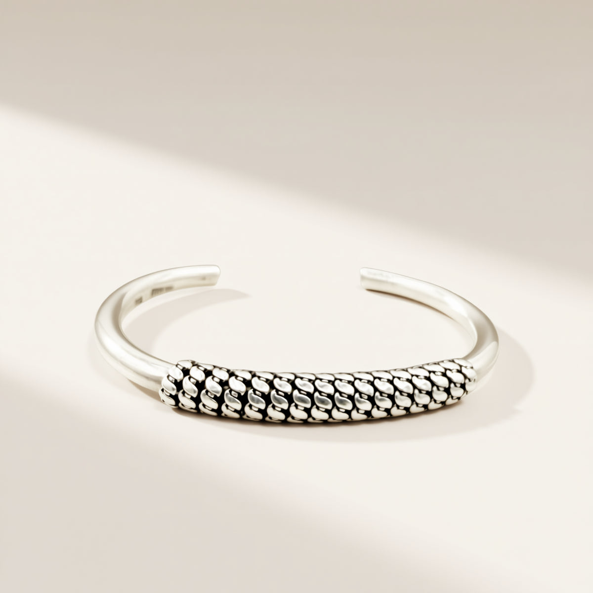 Silver bracelet with textured design on a light beige background