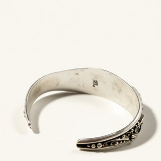 Silver bracelet with intricate design on a white background