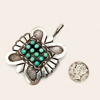 Silver pendant and coin on a beige background