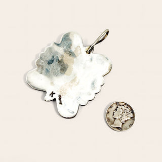 Silver pendant and coin on a beige background