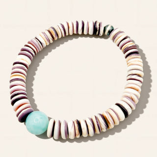 Multicolored beaded bracelet with a central turquoise bead on a light background