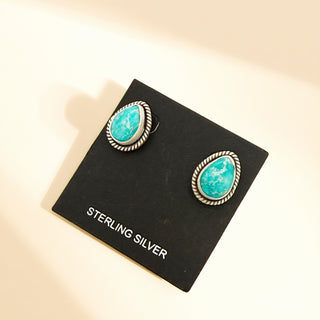 Turquoise earrings on a black card with 'STERLING SILVER' text, against a beige background