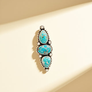 Jewelry with three turquoise stones on a beige background