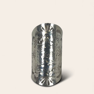 Silver cylindrical object with intricate patterns on a white background